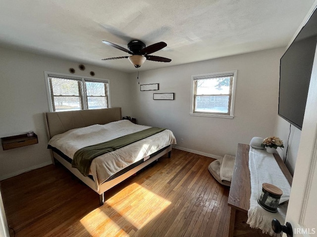 bedroom featuring multiple windows, dark hardwood / wood-style flooring, and ceiling fan