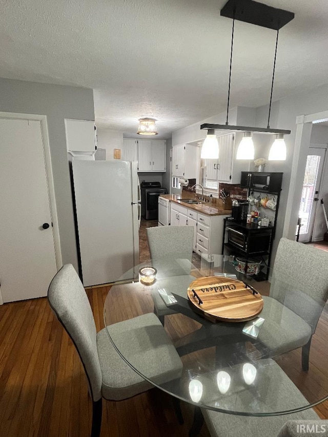 dining room featuring wood-type flooring, sink, and a textured ceiling