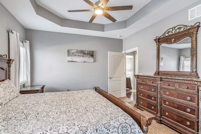 bedroom with ceiling fan and a tray ceiling