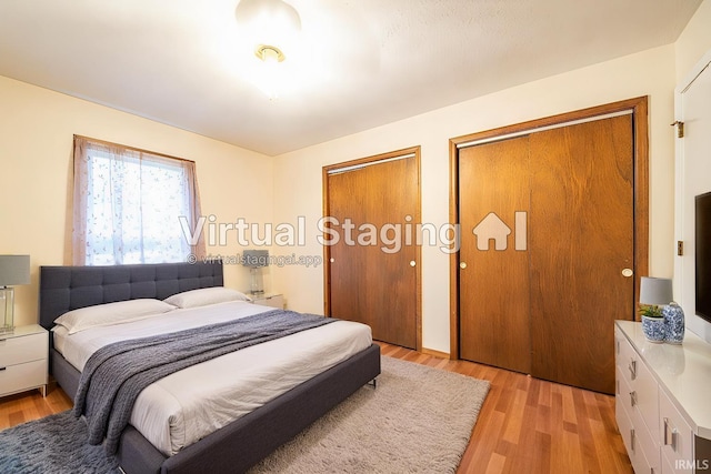 bedroom with light hardwood / wood-style flooring and multiple closets