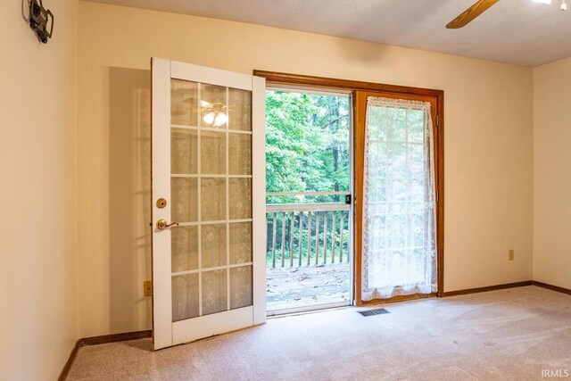 doorway featuring ceiling fan and carpet