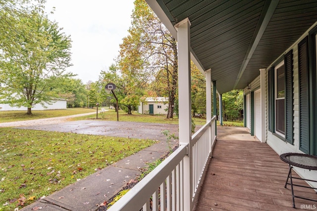 deck featuring covered porch and a yard