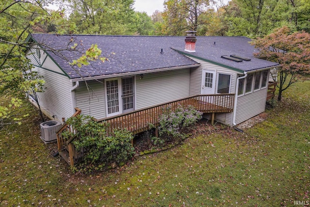 rear view of property featuring a deck, a sunroom, a lawn, and central air condition unit