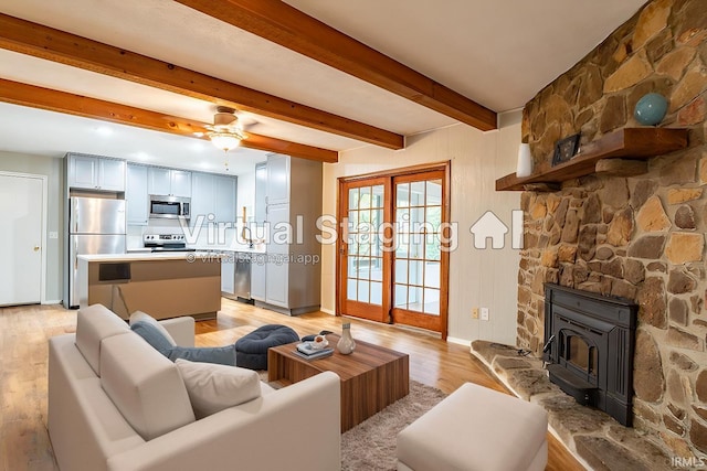 living room featuring ceiling fan, light wood-type flooring, and beamed ceiling