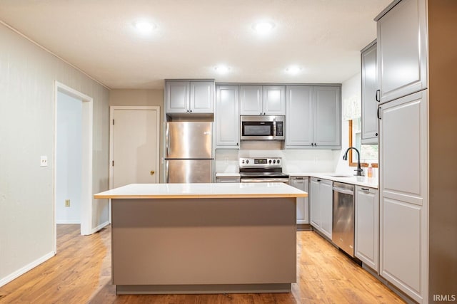 kitchen with stainless steel appliances, light hardwood / wood-style floors, a kitchen island, and sink