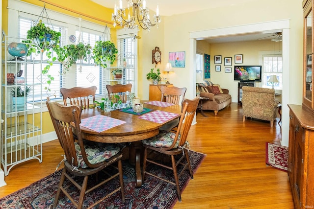 dining area featuring wood-type flooring and ceiling fan with notable chandelier