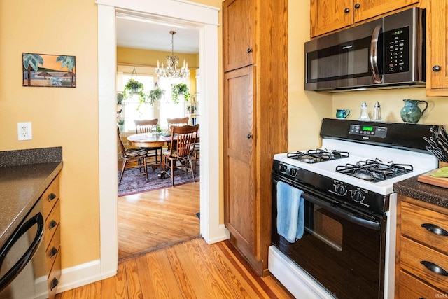 kitchen featuring dishwashing machine, range with gas stovetop, decorative light fixtures, light hardwood / wood-style floors, and a notable chandelier