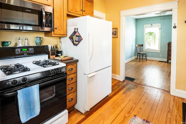 kitchen featuring white refrigerator, range with gas stovetop, and light hardwood / wood-style flooring