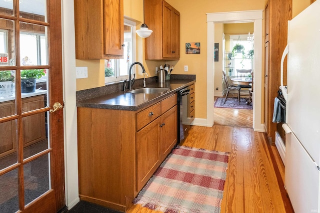 kitchen with decorative light fixtures, light wood-type flooring, dishwasher, white refrigerator, and sink