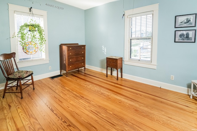 sitting room featuring light wood-type flooring and a healthy amount of sunlight