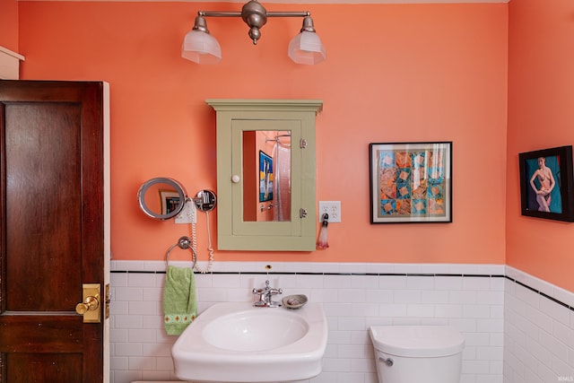 bathroom featuring sink, tile walls, and toilet