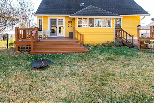 back of property featuring a lawn, a wooden deck, and a fire pit