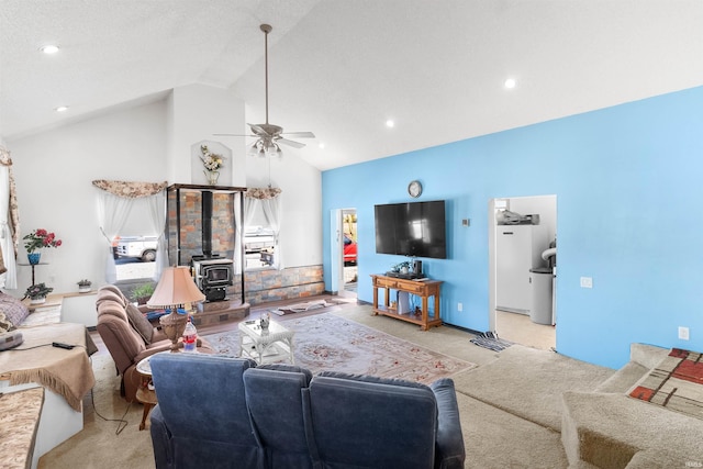 carpeted living room with ceiling fan, a wood stove, and vaulted ceiling