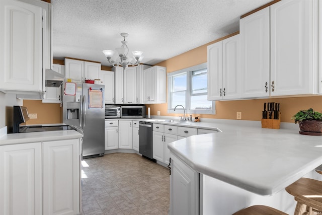 kitchen featuring kitchen peninsula, sink, a kitchen breakfast bar, stainless steel appliances, and white cabinets