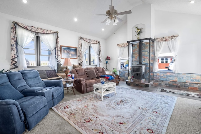 living room featuring ceiling fan, a wood stove, wood-type flooring, and high vaulted ceiling