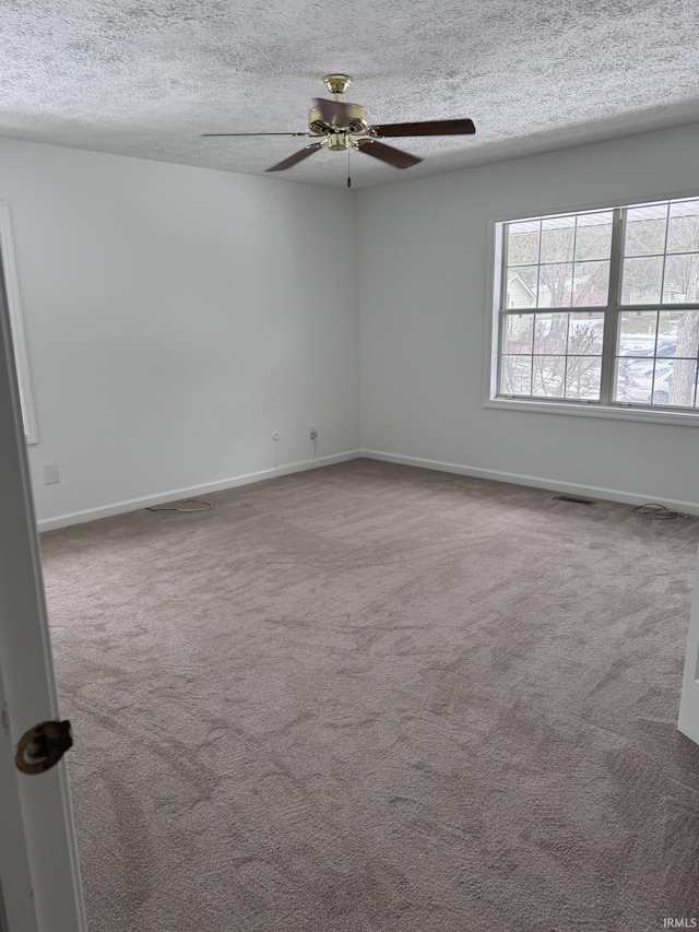 empty room with carpet floors, ceiling fan, and a textured ceiling