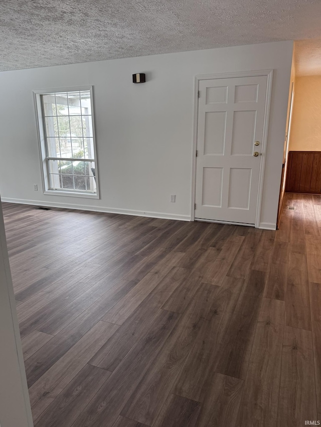 spare room with a textured ceiling and dark wood-type flooring