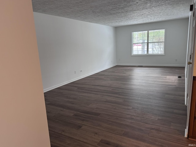 empty room with a textured ceiling and dark hardwood / wood-style flooring