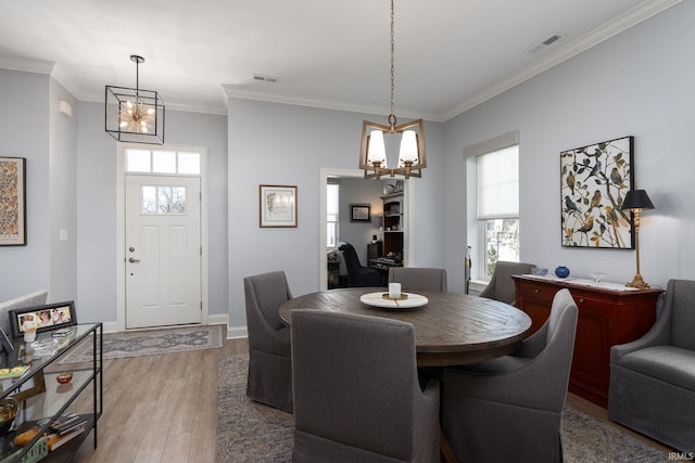 dining space with a notable chandelier, crown molding, and hardwood / wood-style floors