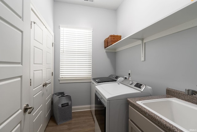 washroom with dark hardwood / wood-style flooring, washer and clothes dryer, and sink