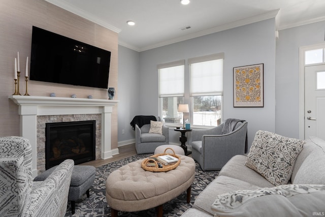 living room with a tiled fireplace, ornamental molding, and hardwood / wood-style flooring