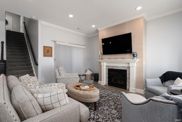 living room with hardwood / wood-style floors, ornamental molding, and a tiled fireplace