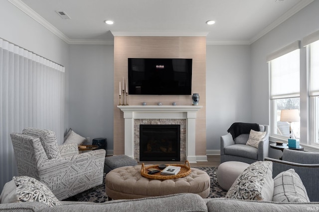 living room featuring wood-type flooring, a tile fireplace, and ornamental molding