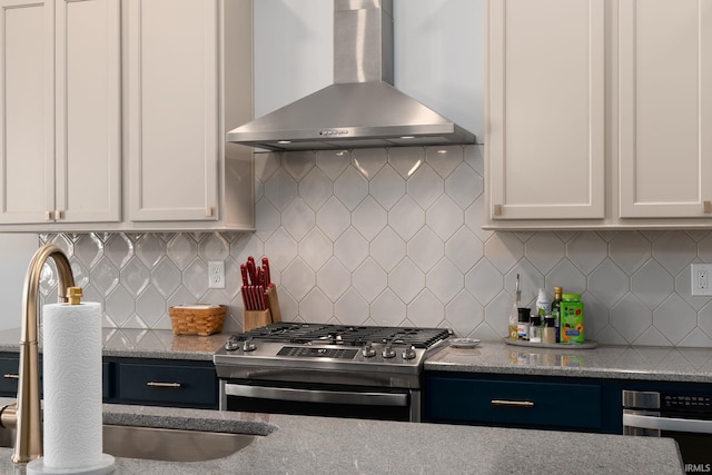 kitchen featuring stainless steel appliances, white cabinets, backsplash, and wall chimney range hood