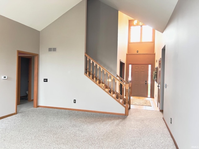 carpeted entryway with high vaulted ceiling