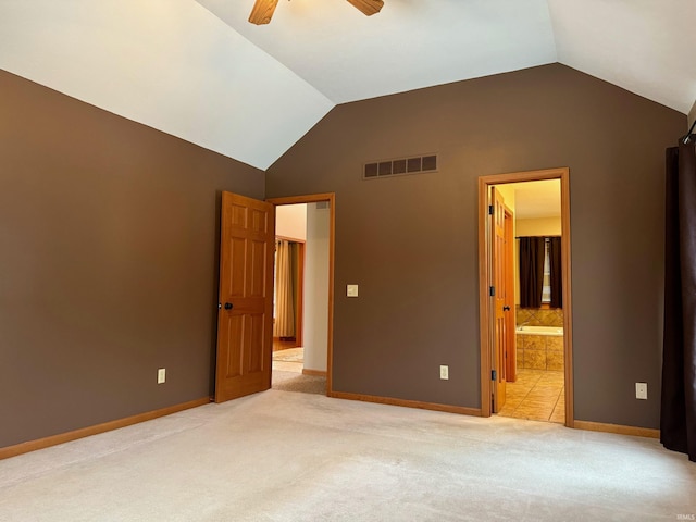 unfurnished bedroom featuring ceiling fan, ensuite bathroom, lofted ceiling, and light carpet