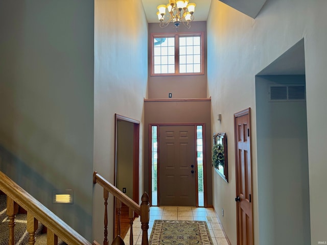 entryway with light tile patterned floors, a chandelier, and a towering ceiling