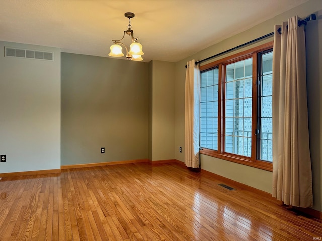 unfurnished room with a chandelier and light hardwood / wood-style flooring