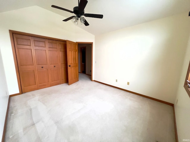 unfurnished bedroom featuring ceiling fan, light colored carpet, a closet, and lofted ceiling