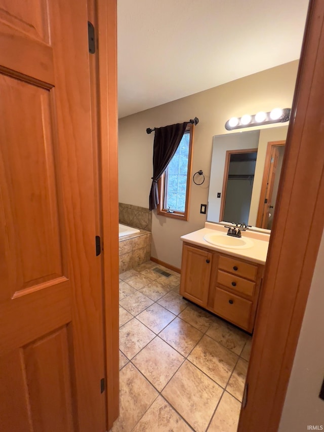 bathroom with tiled tub, tile patterned floors, and vanity