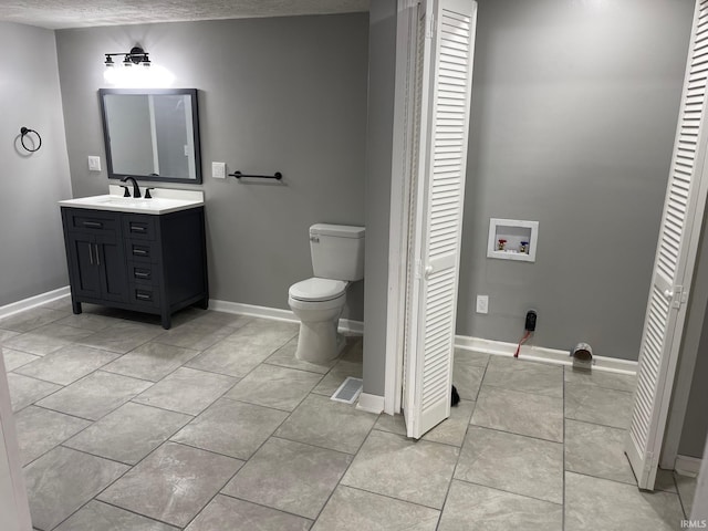 bathroom featuring a textured ceiling, toilet, vanity, and tile patterned flooring