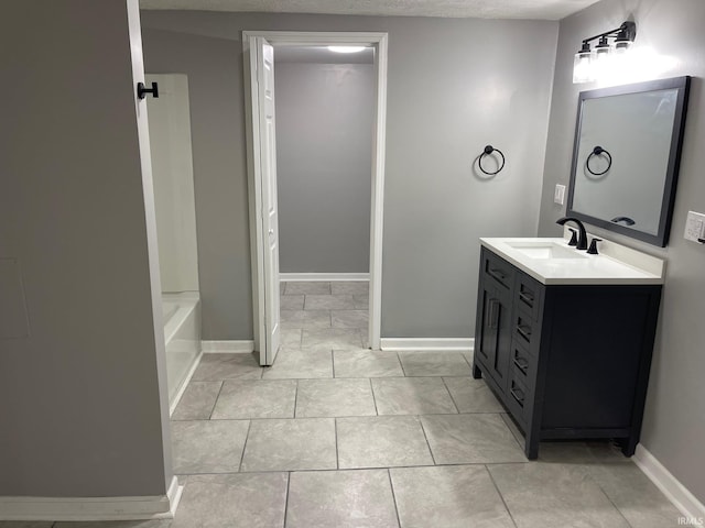 bathroom with a textured ceiling, tile patterned floors, and vanity