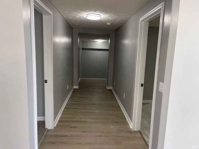 hall with a textured ceiling and hardwood / wood-style floors