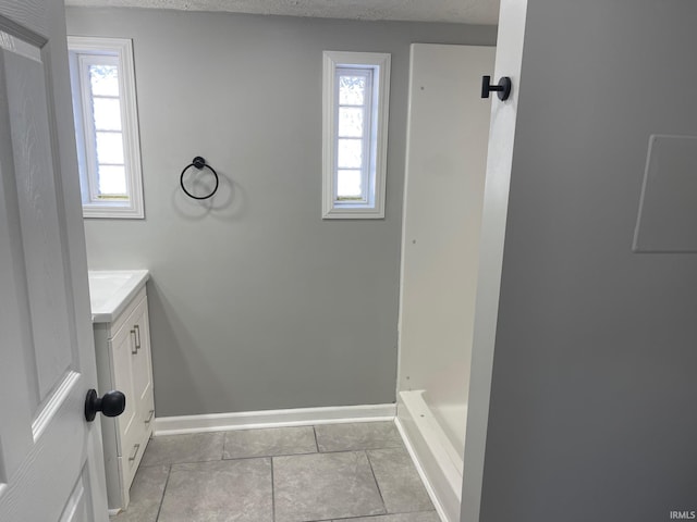 bathroom featuring a textured ceiling, walk in shower, tile patterned floors, and vanity