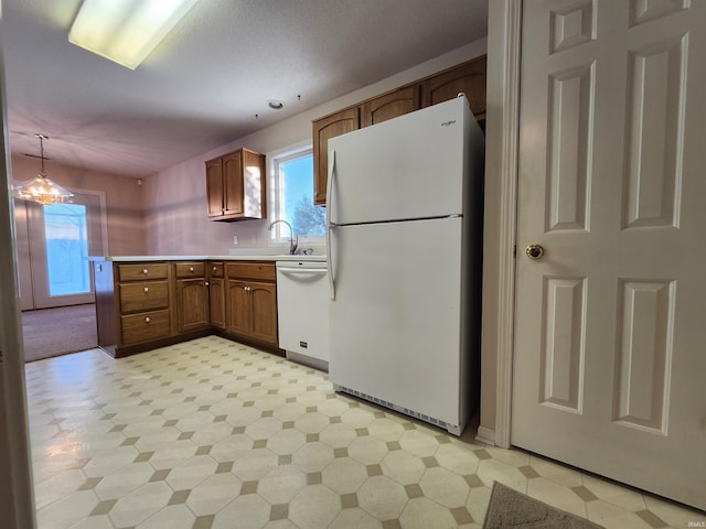 kitchen featuring decorative light fixtures, an inviting chandelier, sink, and white appliances