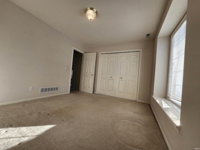 unfurnished bedroom featuring a closet and light colored carpet