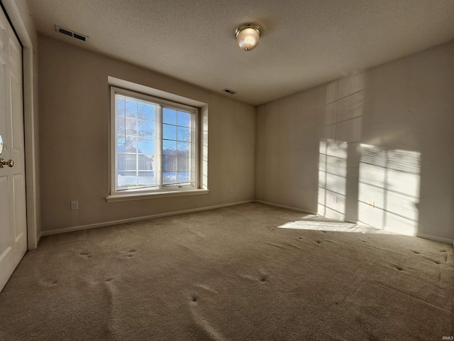 carpeted empty room with a textured ceiling