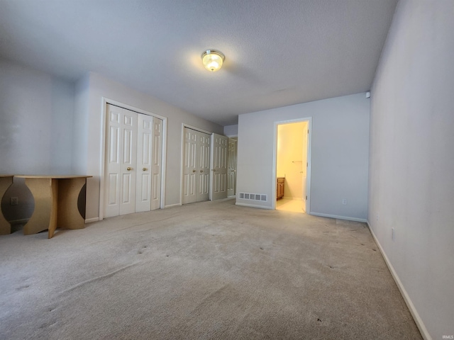 carpeted bedroom with two closets and ensuite bath