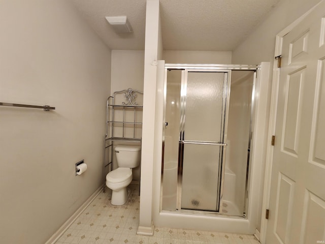 bathroom with an enclosed shower, toilet, and a textured ceiling