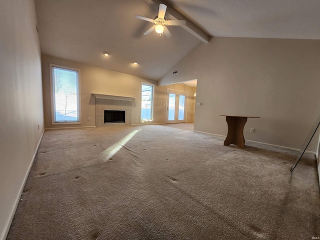 unfurnished living room featuring carpet flooring, beam ceiling, plenty of natural light, and a tile fireplace