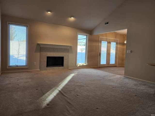 unfurnished living room with carpet, lofted ceiling, and a tiled fireplace