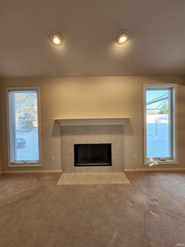 unfurnished living room with light colored carpet, a healthy amount of sunlight, and a fireplace