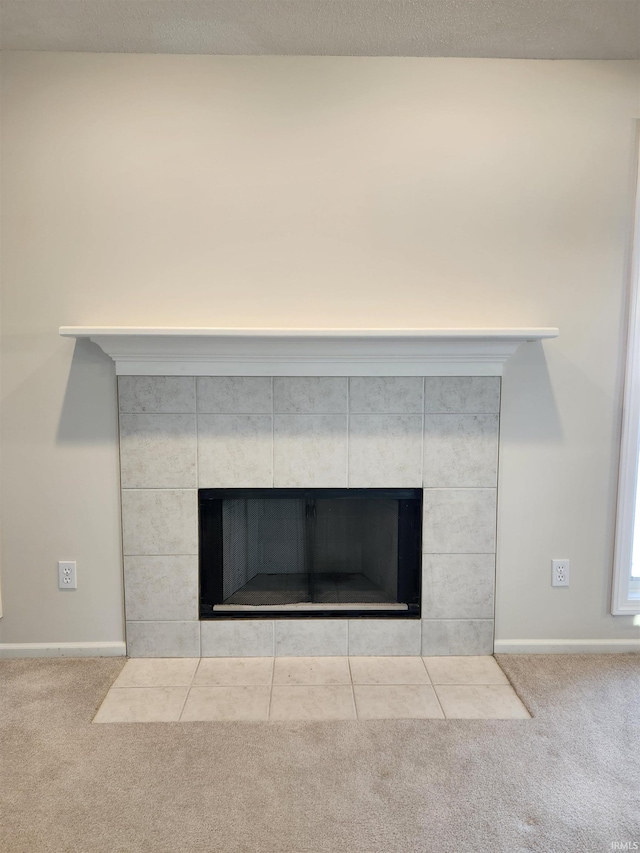 interior details featuring a tiled fireplace and carpet floors