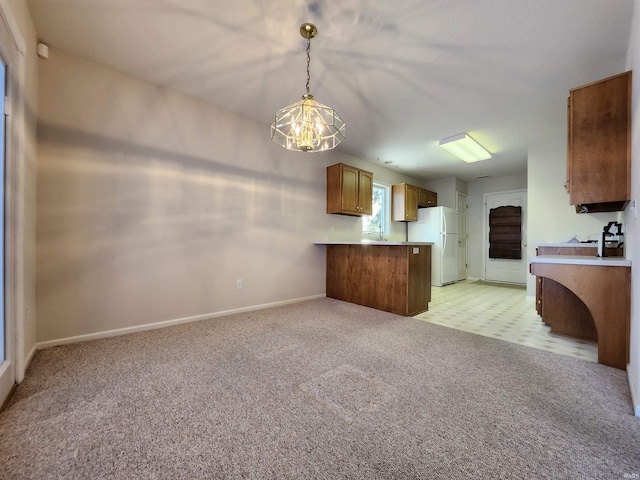 kitchen with kitchen peninsula, decorative light fixtures, light colored carpet, a chandelier, and white refrigerator