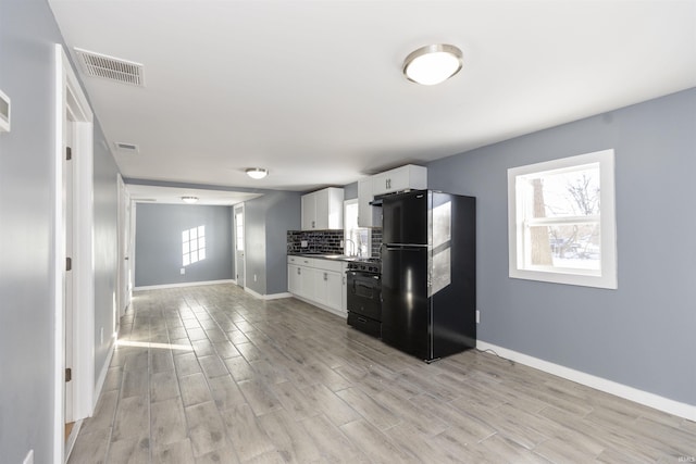 kitchen featuring black appliances, a healthy amount of sunlight, backsplash, and white cabinetry