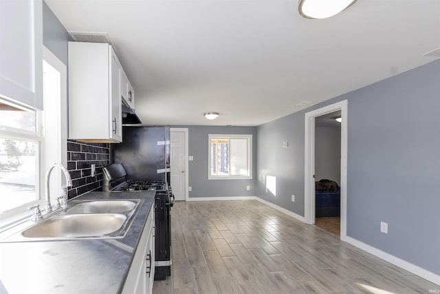 kitchen featuring backsplash, sink, white cabinetry, light wood-type flooring, and range with gas stovetop